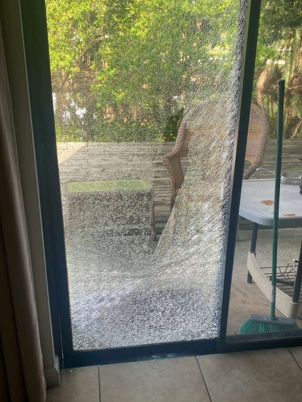 Shattered sliding glass door panel still in its frame, seen from inside the home