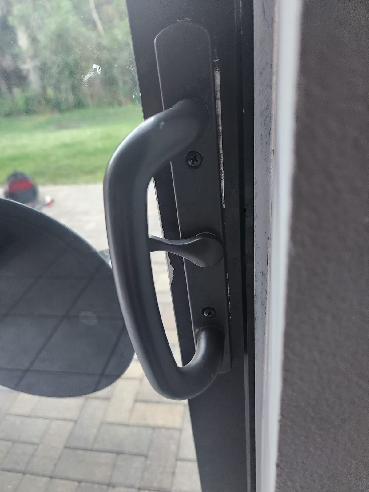 Close-up of a black sliding door handle and latch on the edge of a sliding glass door