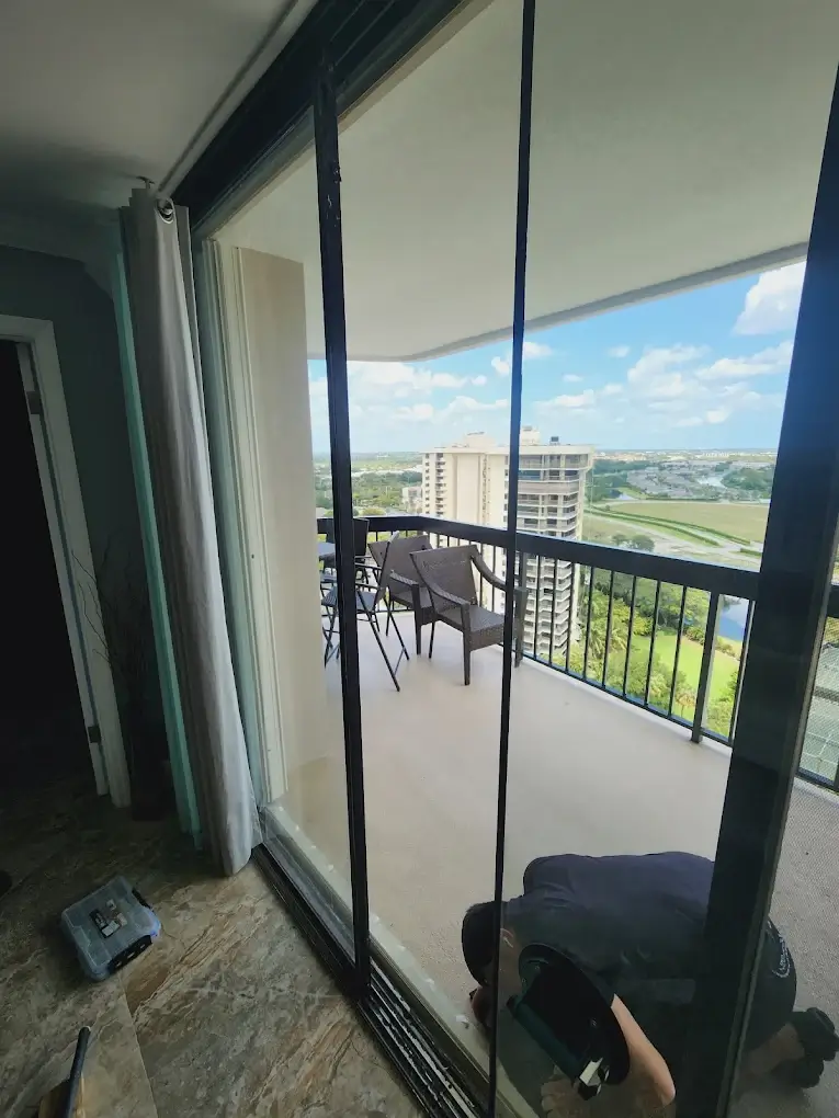 Nexora technician repairing a sliding glass door on a high-rise balcony